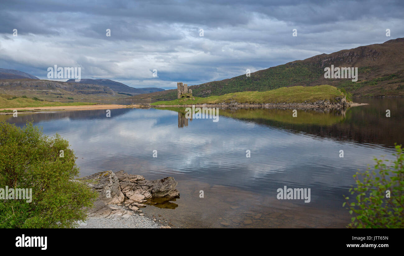 Atemberaubende Landschaft der Highlands mit Loch Assynt mit Ruinen von Ardvreck Castle in Spiegelfläche von Wasser unter stürmischen Himmel in Schottland wider Stockfoto