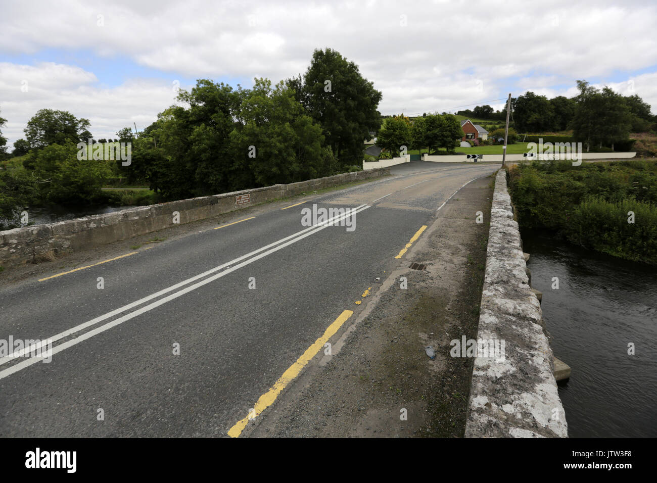 Cullaville, Nordirland. 10. August 2017. Die Grenze zwischen Nordirland und der Republik Irland als auf der Straße Unterschiede auf einer Brücke über den Fluss Fane als Co Monaghan (Straße auf der linken Seite des Rahmens) erfüllt die Co Armagh demonstriert. Die Linie quer über die Straße in der Mitte der Rahmen ist, wo die Grenze auftritt. Credit: Laura Hutton/Alamy Leben Nachrichten. Stockfoto