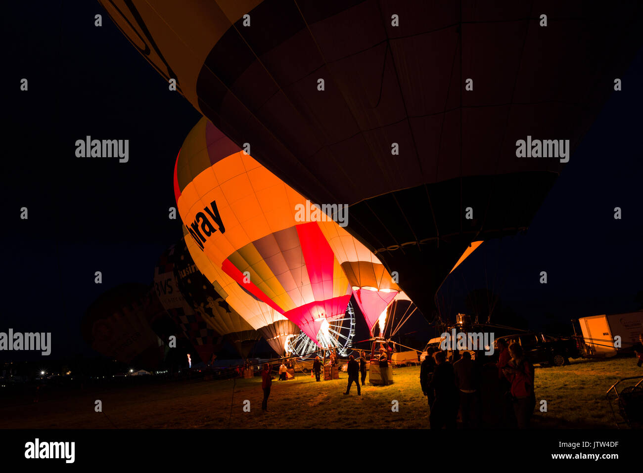 Heißluftballons, die in der Nacht leuchten im Bristol Balloon Fiesta an Ashton Hof, Bristol, England. Stockfoto