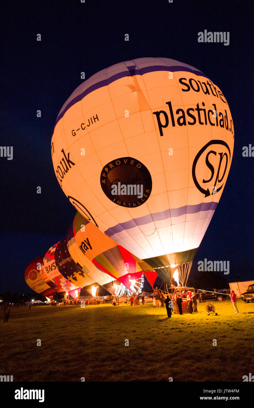 Heißluftballons, die in der Nacht leuchten im Bristol International Balloon Fiesta an Ashton Hof, Bristol, England. Stockfoto