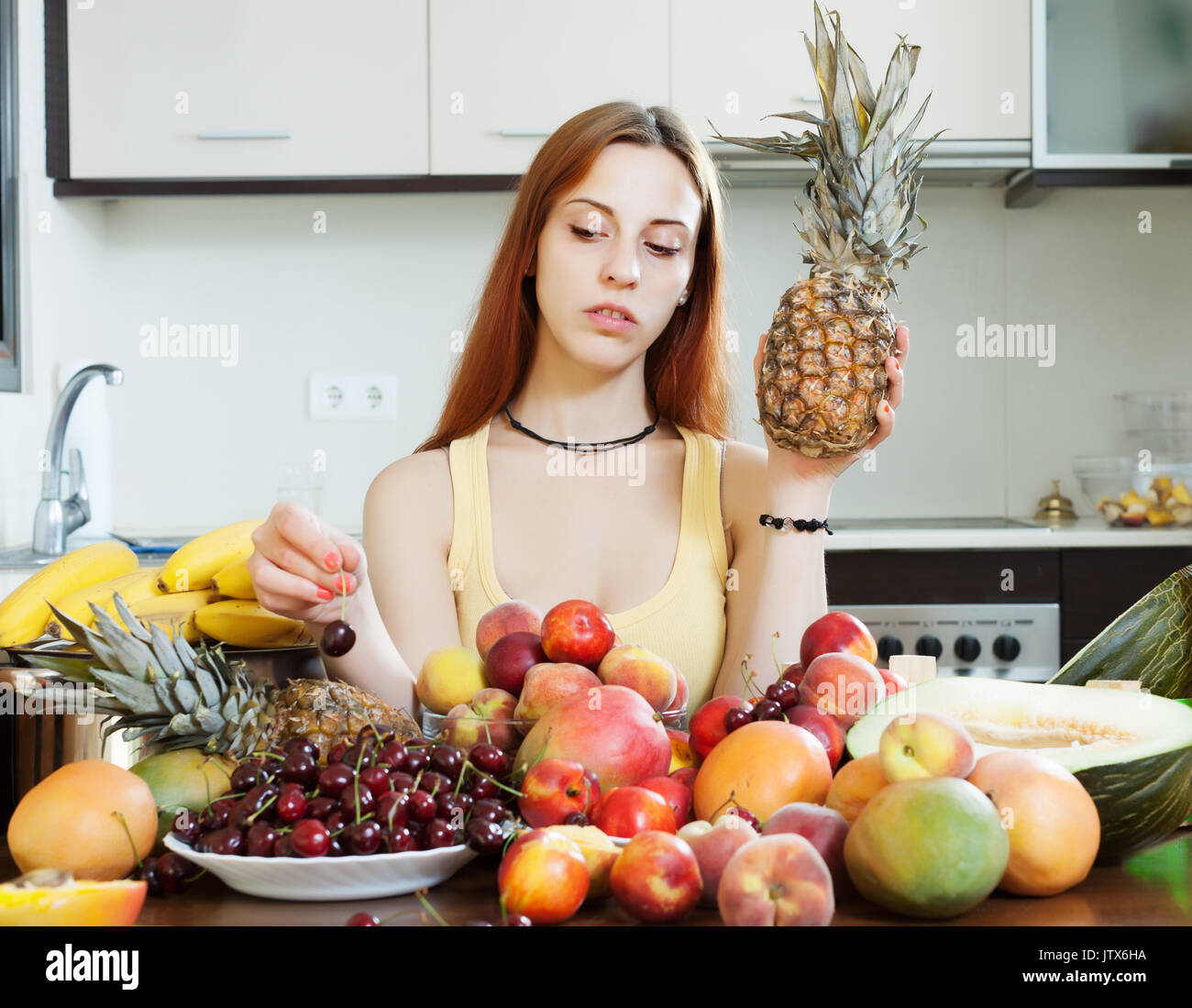 Frau mit Haufen der Früchte in der Küche zu Hause Stockfoto