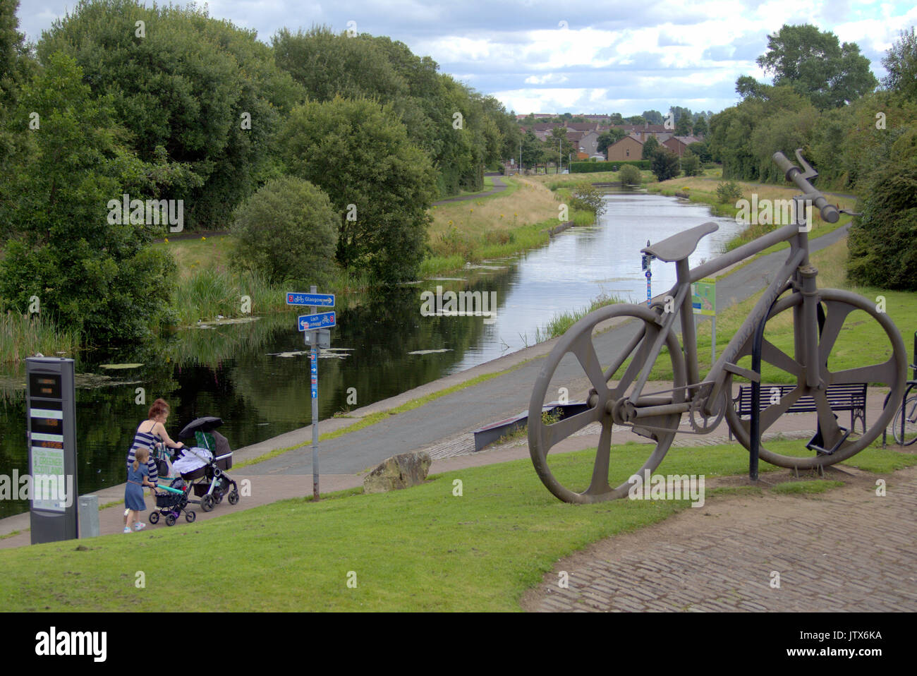 Mutter und Kind sowohl schieben Kinderwagen pass die Bankies bike Skulptur an der Clydebank im Sommer das Wetter auf der Forth-and-Clyde-Kanal Leinpfad NCN 7 Stockfoto