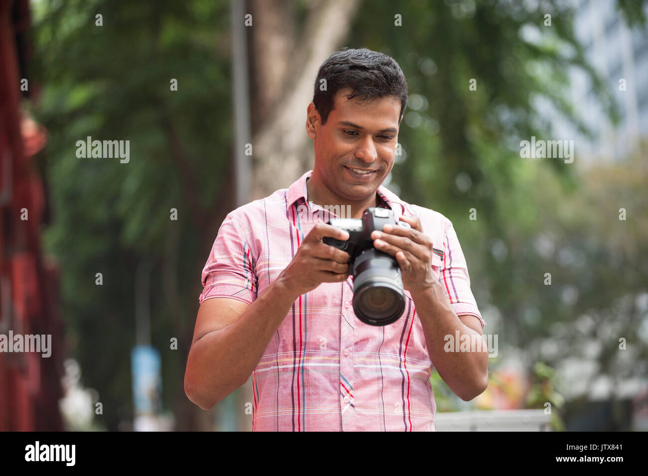 Portrait von Happy indischen Mann die Bilder mit einer Kamera in der Stadt. Asiatische Fotograf Aufnahmen im Freien mit Digitalkamera. Stockfoto