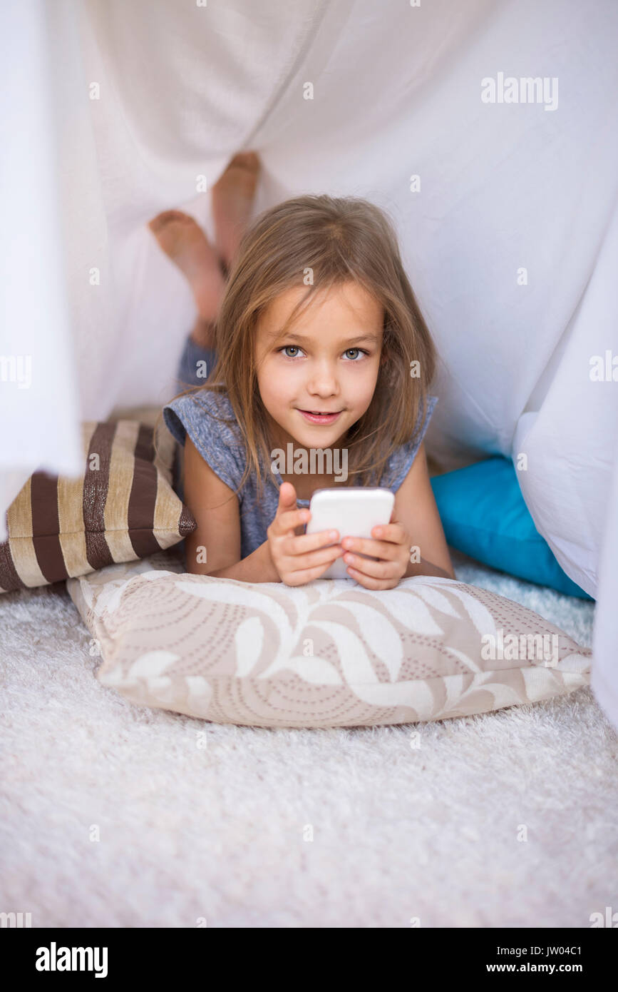 Mädchen liegt auf der Vorderseite und mit einem Mobiltelefon Stockfoto