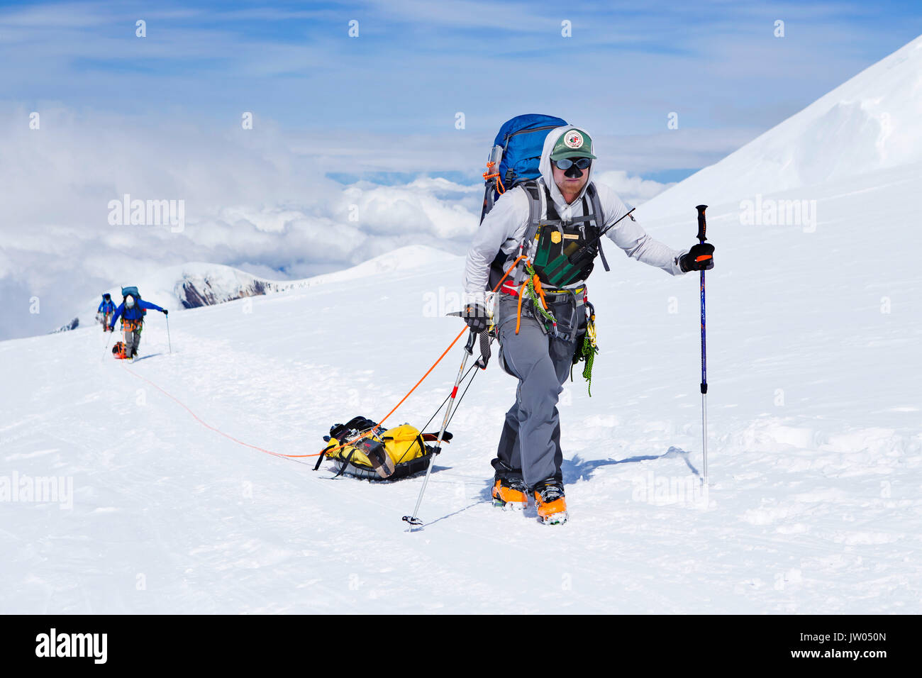 Skitourengeher und Förster auf dem Weg zu 14.000 Fuß auf Haines in Alaska. Bergsteiger auf dem höchsten Gipfel der nördlichen Amerika tragen die Lasten in die Rucksäcke und auf Schlitten. Stockfoto