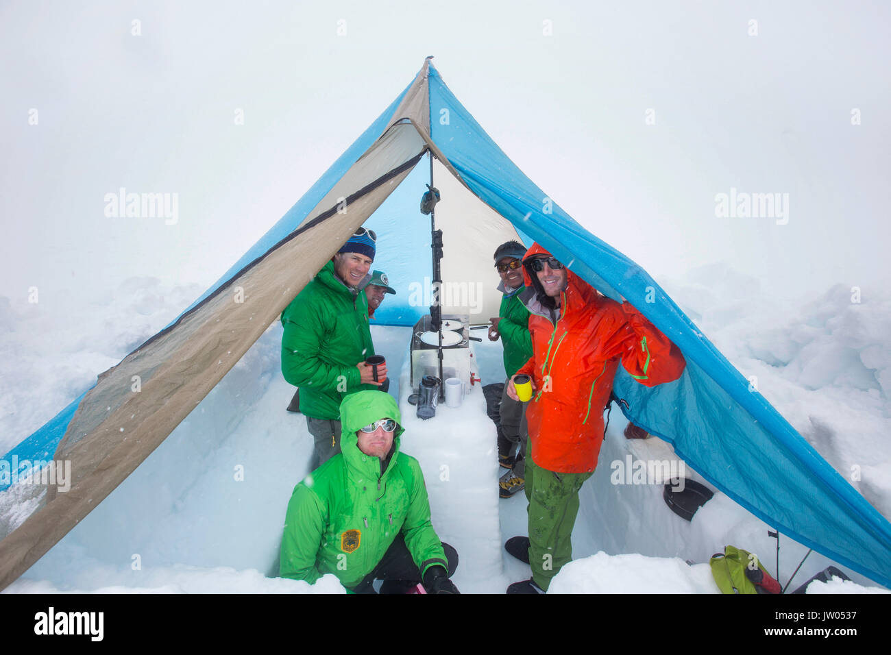 Fünf Bergsteiger sind, Zuflucht in einem Zelt auf der unteren Kahiltna-gletscher auf Haines in Alaska. Sie sind schmelzenden Schnee Essen zu kochen und haben warme Getränke. Stockfoto