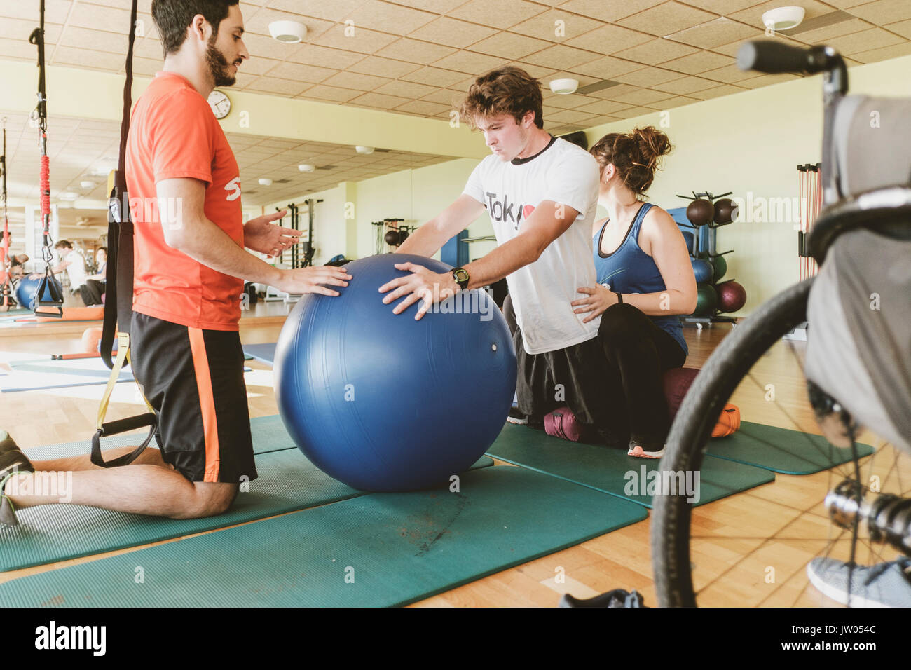 Junger Mann üben mit Kugel an Physiotherapie Sitzung Stockfoto