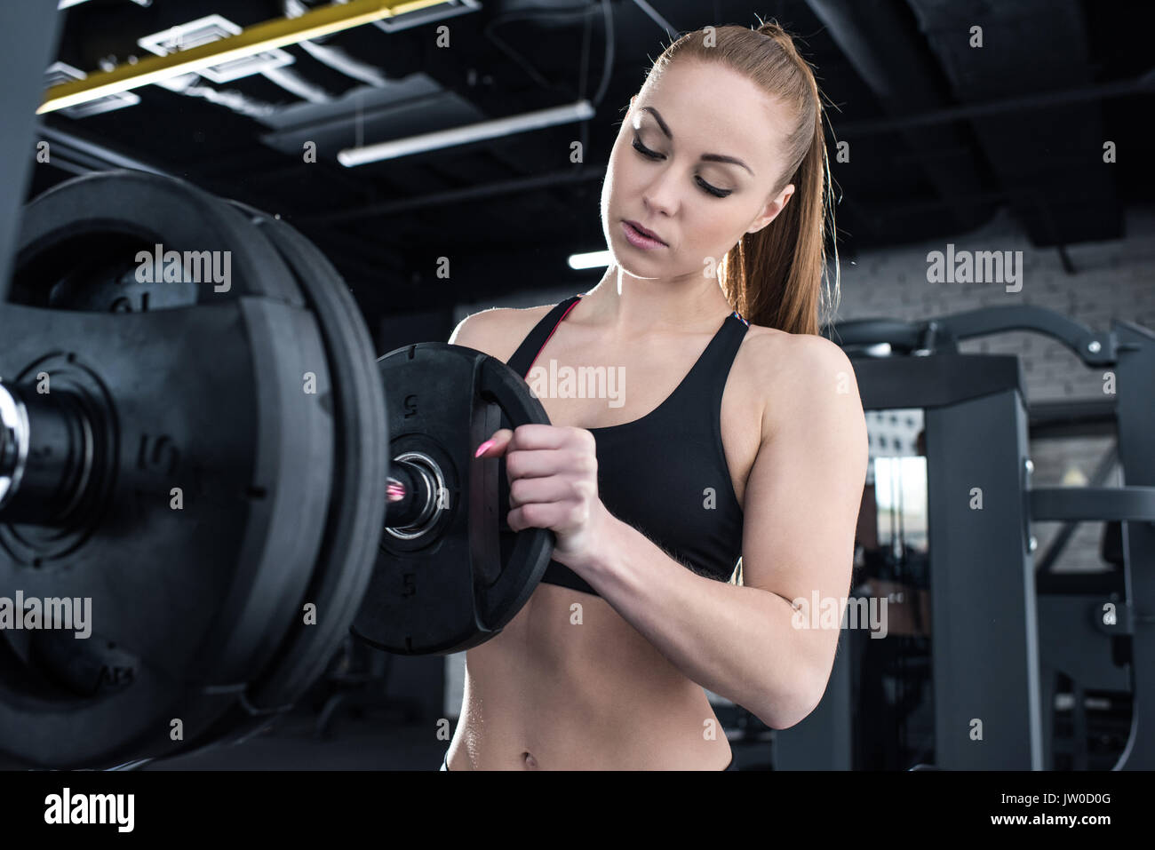 Muskulöse junge Frau, Gewicht auf die Hantel in der Turnhalle Stockfoto