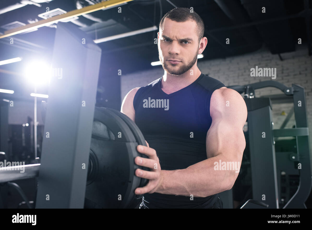 Ernsthafte muskulöse Sportler das Gewicht auf der Hantel und Kamera in der Turnhalle Stockfoto