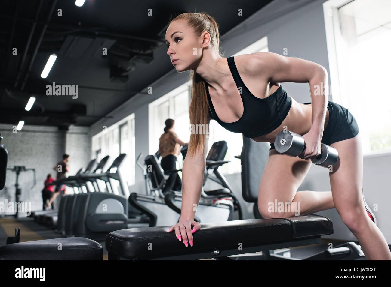 Junge konzentriert sportliche Frau mit Hantel Training im Fitnessstudio Stockfoto