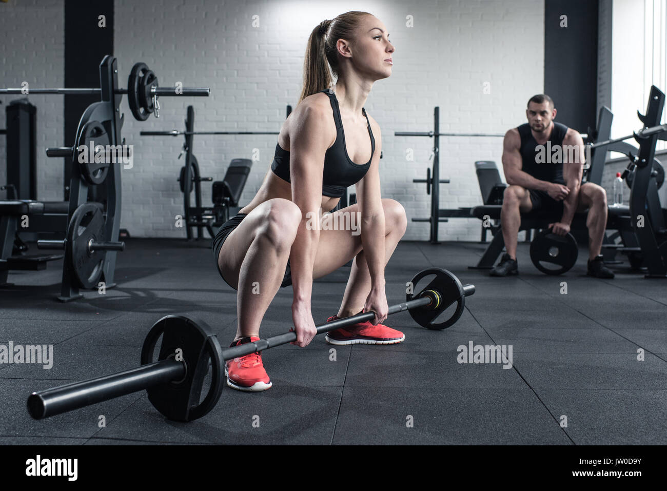Frau tun Krafttraining mit Langhantel während man im Fitnessstudio sitzen Stockfoto