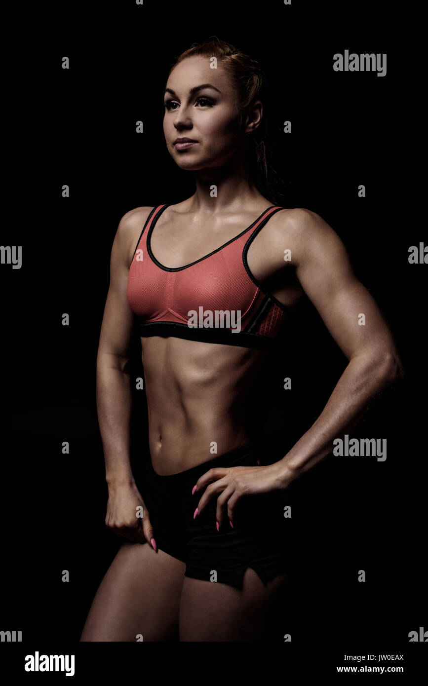 Muskulöse Sportlerin posiert in Sportswear und zeigen ihren schlanken Körper auf Schwarz isoliert Stockfoto