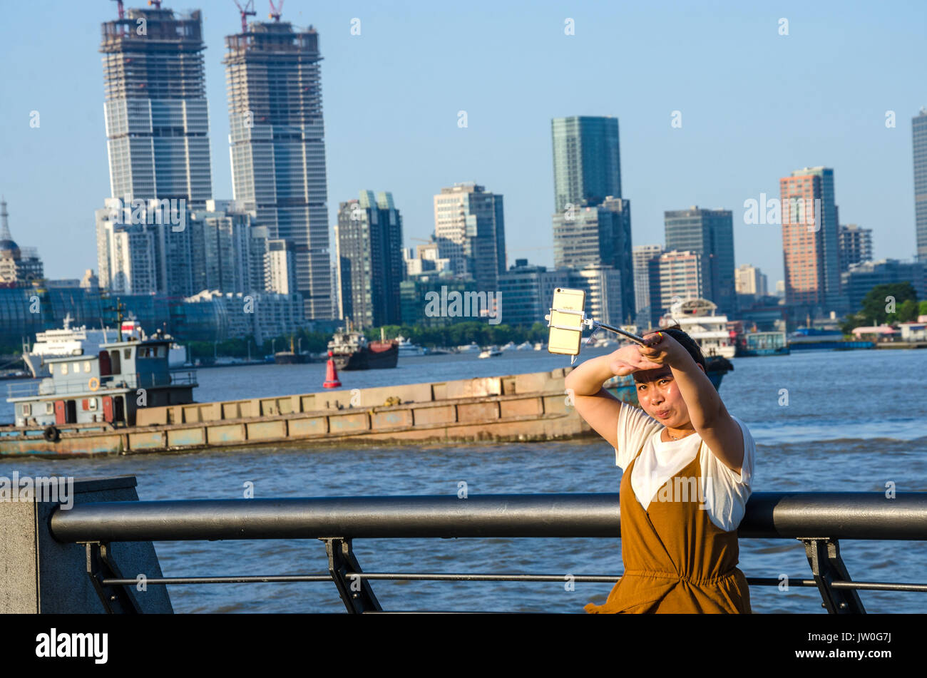 Eine Dame nimmt eine selfie mit den Fluss Huangpu in Shanghai, China, in den Hintergrund. Stockfoto