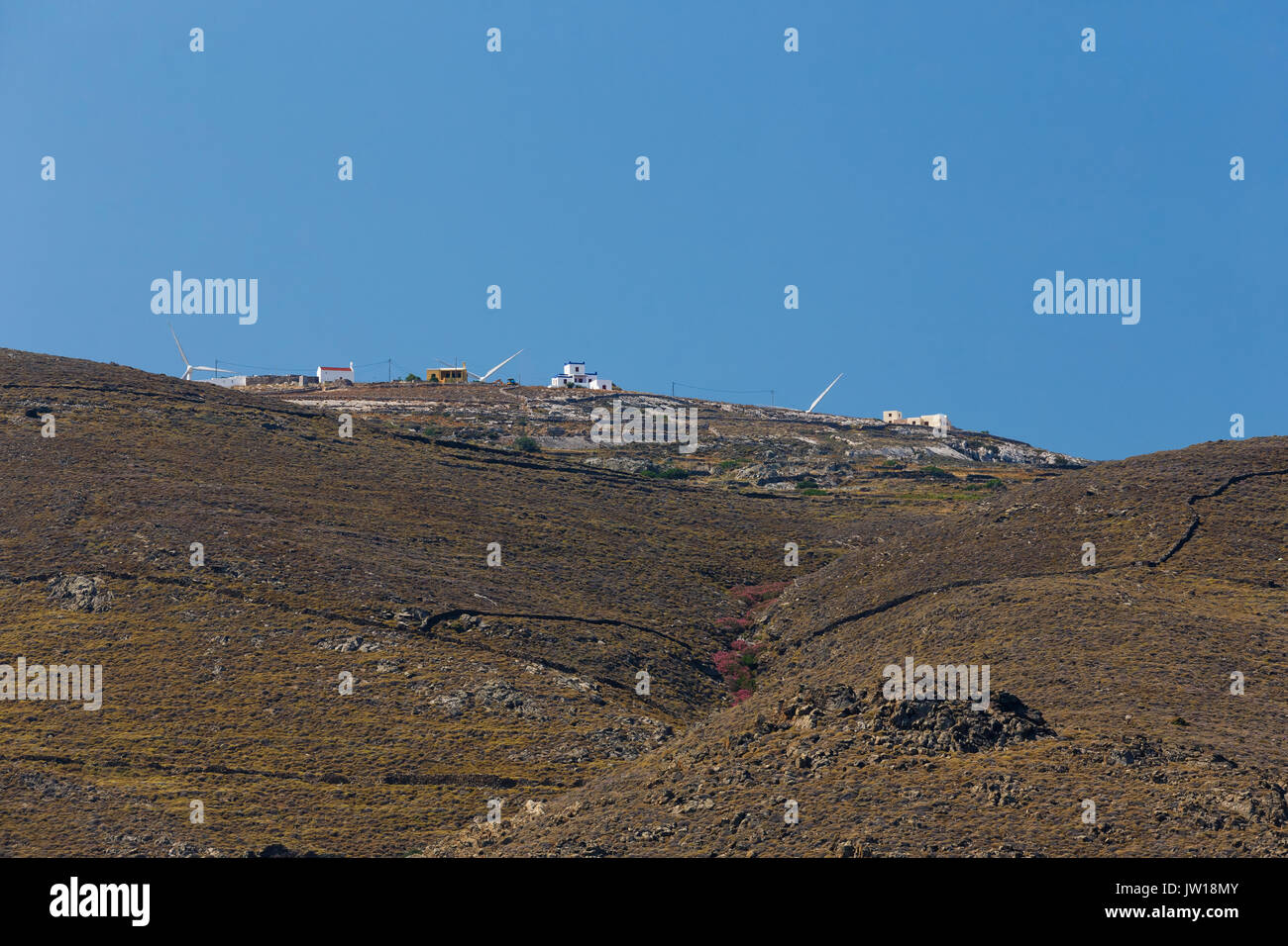 Schöne raw Landschaft auf der Insel Syros, Griechenland gegen ein blauer Himmel und kleines Dorf auf Abstand Stockfoto