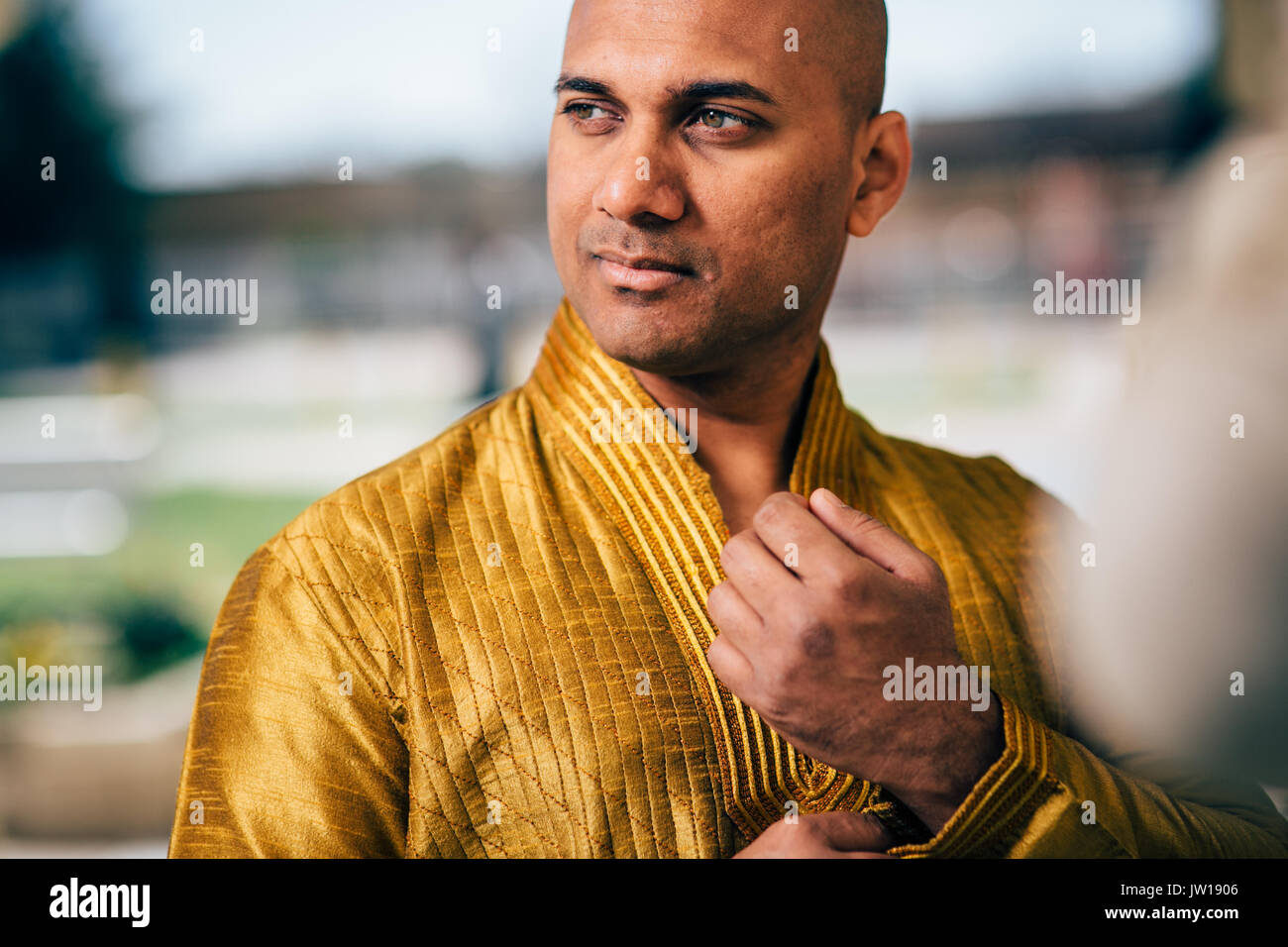 Die schönen Indischen Mann trägt ein gold Kurta und stellte an einem Tempel. Stockfoto