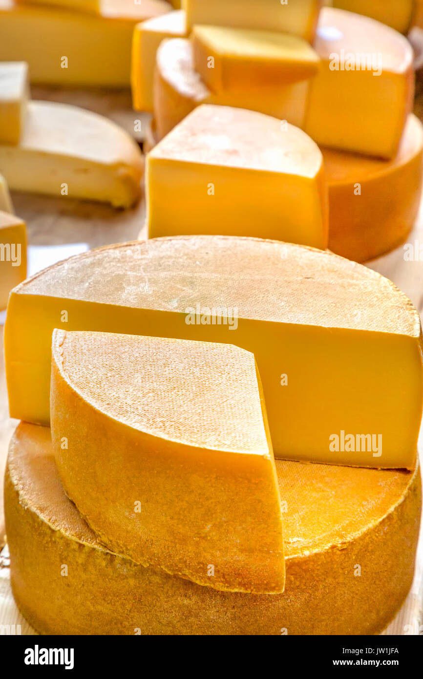Käse Köpfe mit einer Scheibe abgeschnitten auf hölzernen Tisch Stockfoto