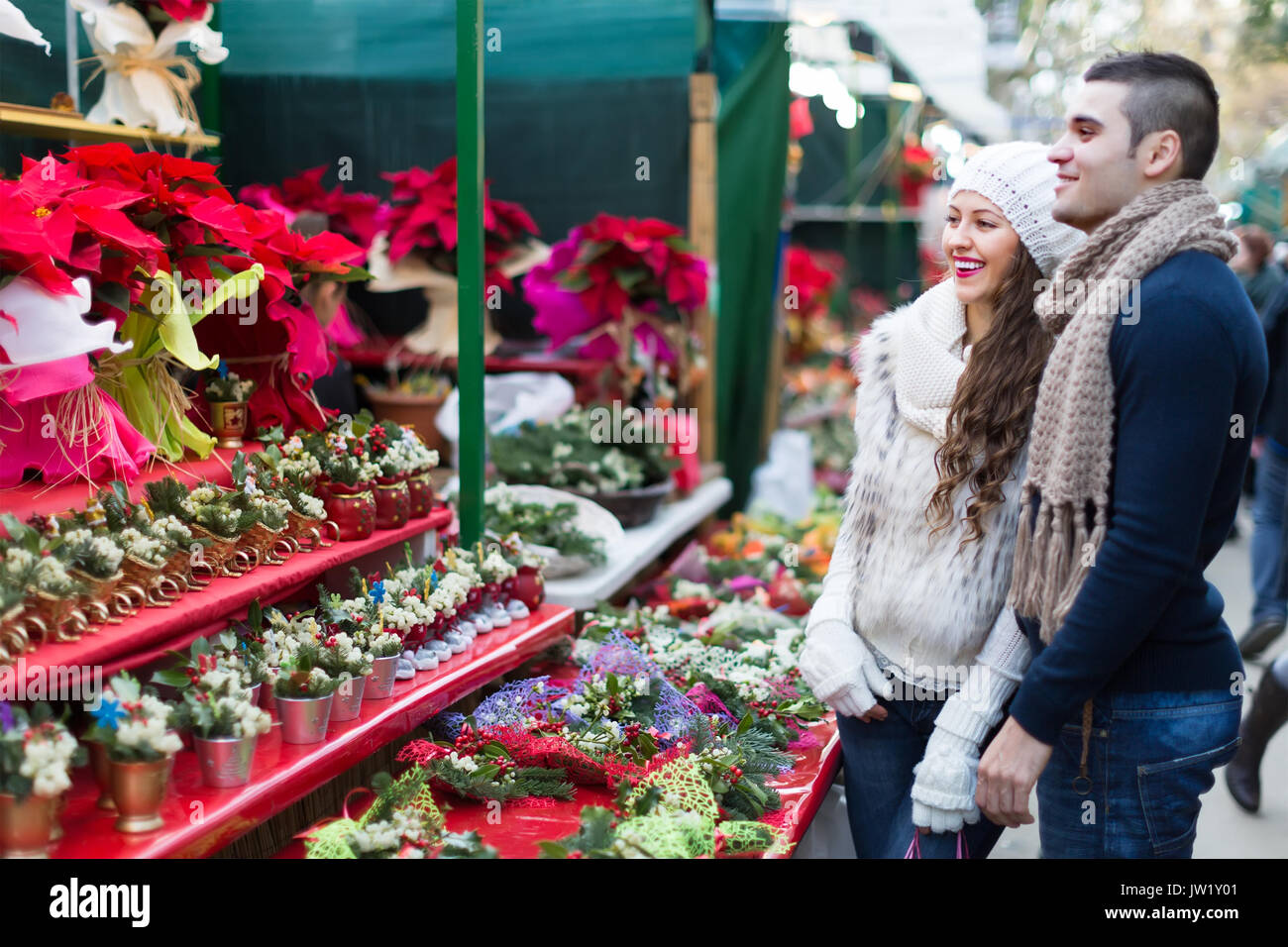 Glücklich lächelnde junge Paar kaufen Christmas Star Blume am Markt. Flache Tiefenschärfe Stockfoto