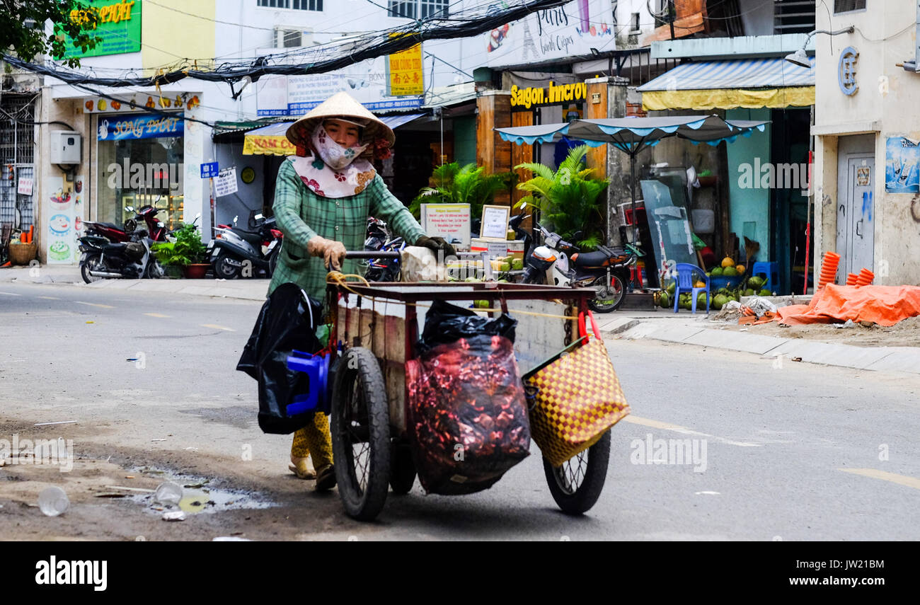 Eine weibliche Vietnamesische Straßenhändler schiebt einen Einkaufswagen entlang einer Straße in Ho Chi Minh City, Vietnam Stockfoto