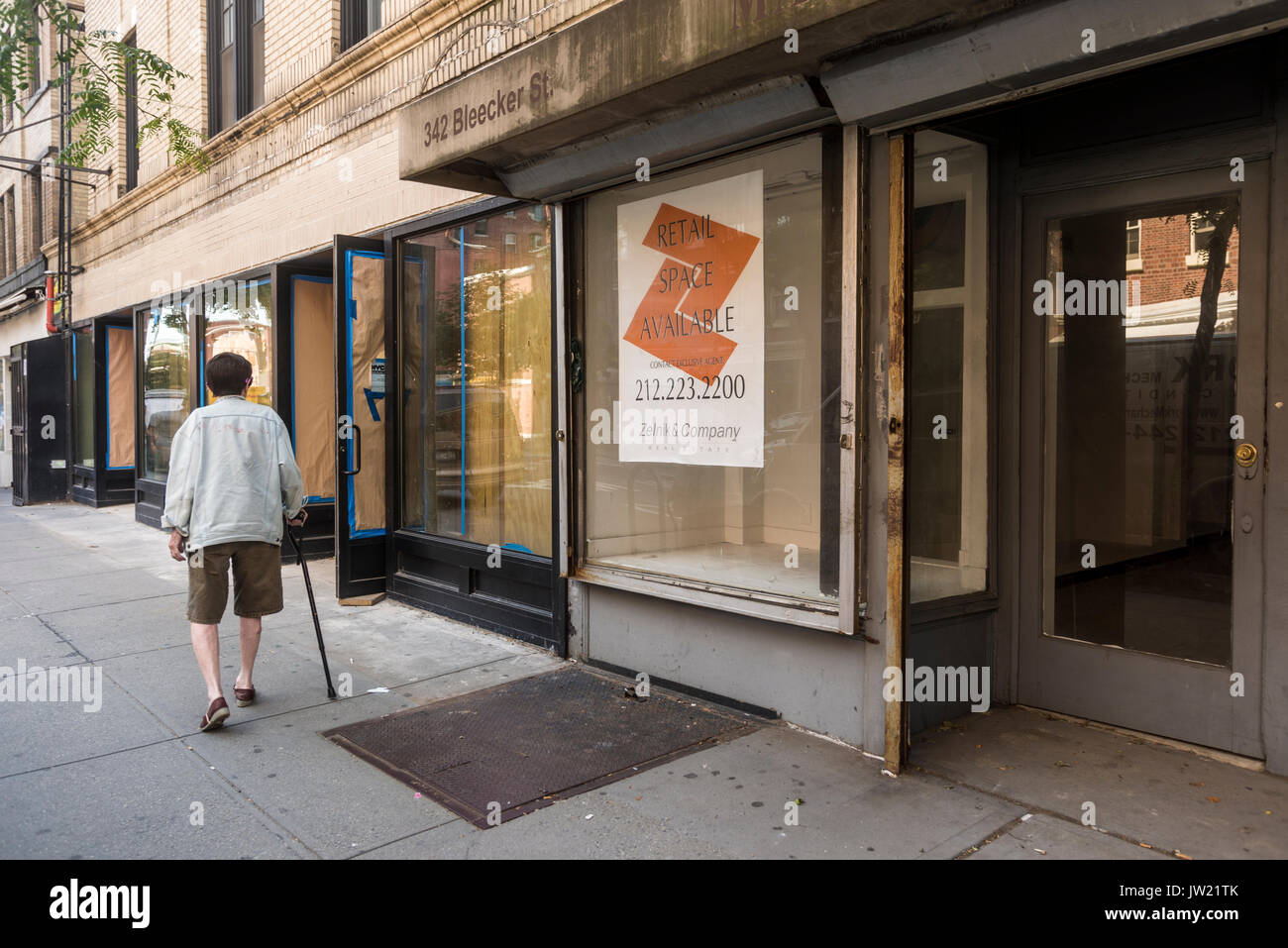 New York, NY, USA - Eine ältere Frau mit einem Stock Wanderungen vorbei an einigen der vielen Leere Läden für Miete auf Bleecker Street, unbesetzt bleibt aufgrund der hohen Mieten. © Stacy Walsh Rosenstock Stockfoto