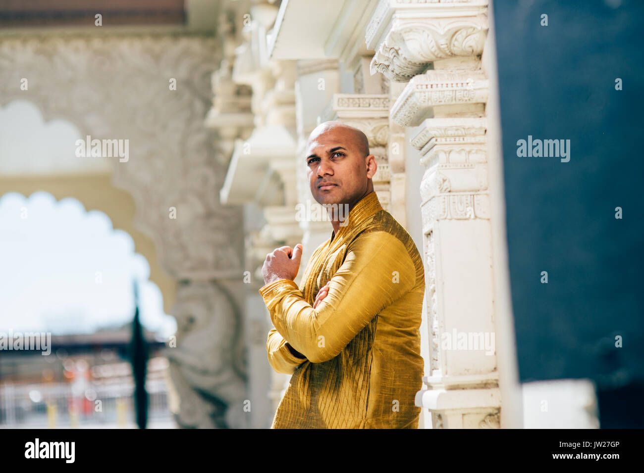 Die schönen Indischen Mann trägt ein gold Kurta und stellte an einem Tempel. Stockfoto