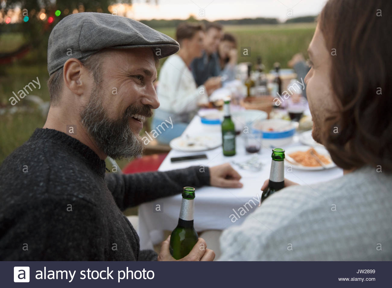 Lächelnd mann Bier trinken und reden an Freund im Summer Garden Party Abendessen Stockfoto