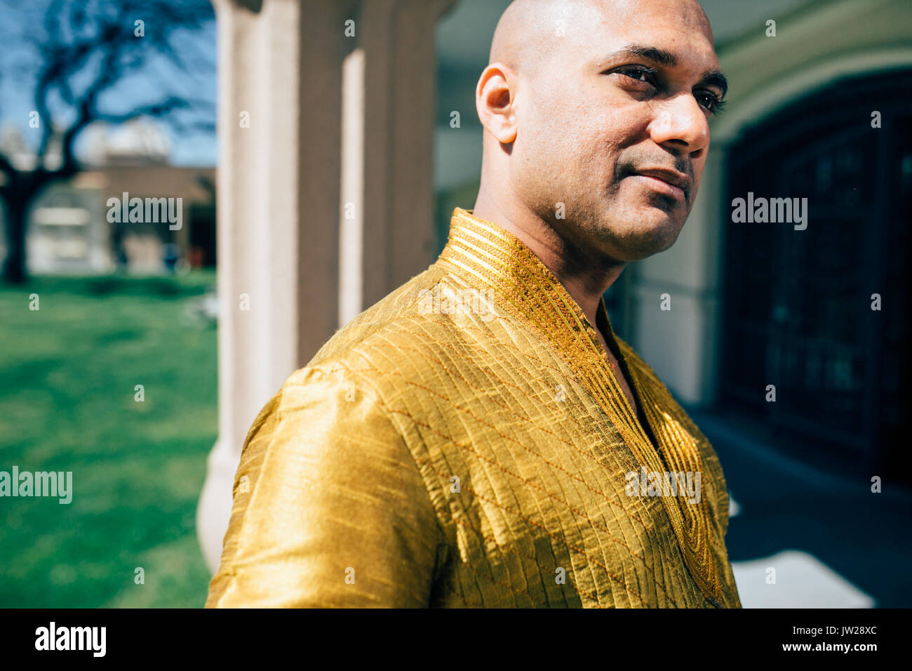 Die schönen Indischen Mann trägt ein gold Kurta und stellte an einem Tempel. Stockfoto