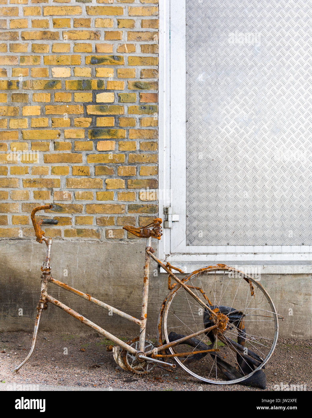 Alten rostigen Fahrrad mit fehlenden Vorderrad gegen die Wand gelehnt. Von der Ein- oder Ausgang der Wasserkraftwerk in Floda, Schweden entfernt. Model Release: Nein Property Release: Nein. Stockfoto