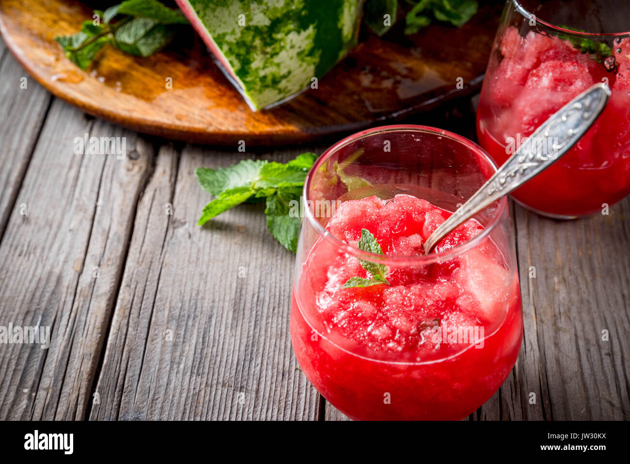 Sommer Obst Desserts, Frozen Cocktails. Eis Granit von Wassermelone mit Minze, portioniert in Gläsern, mit Scheiben von Wassermelone. Auf alten rustikalen w Stockfoto