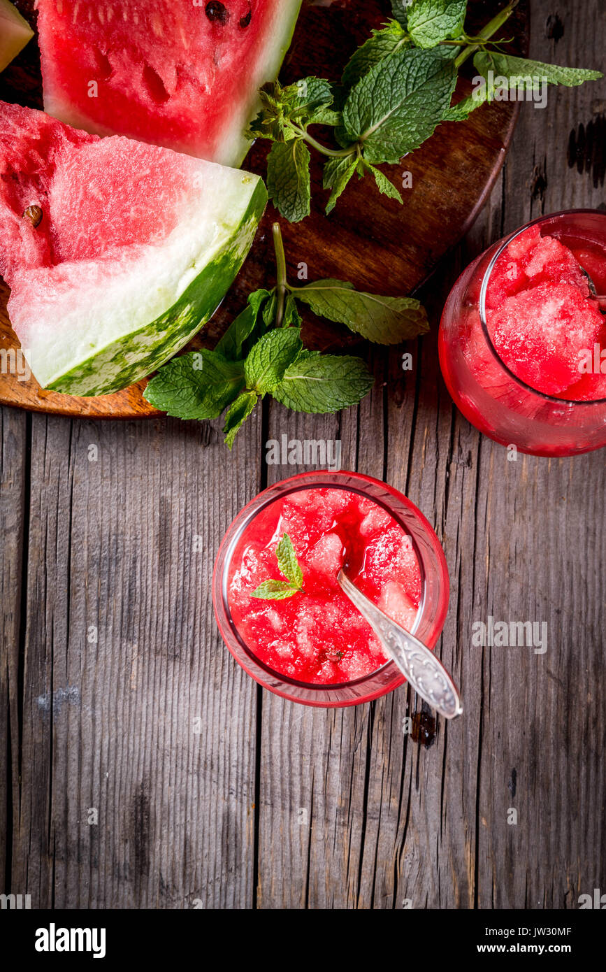 Sommer Obst Desserts, Frozen Cocktails. Eis Granit von Wassermelone mit Minze, portioniert in Gläsern, mit Scheiben von Wassermelone. Auf alten rustikalen w Stockfoto