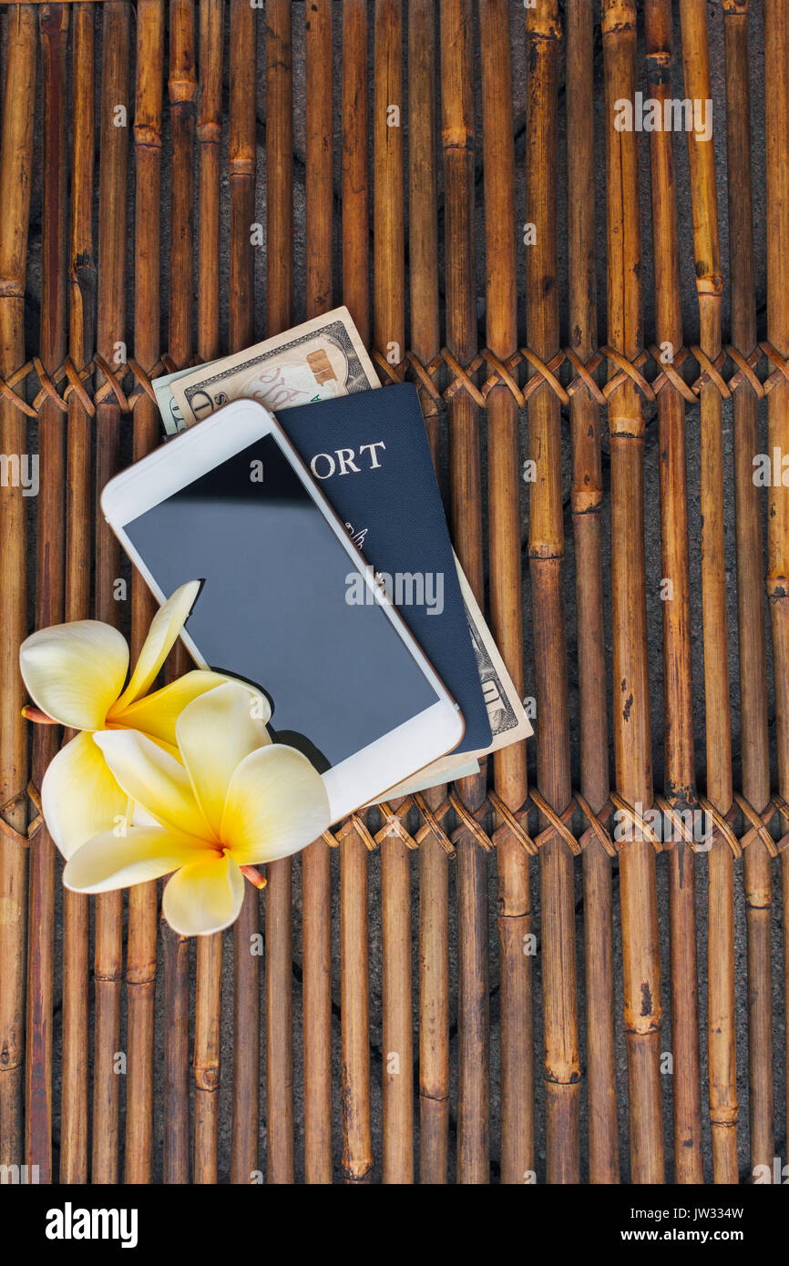 Reisepass mit amerikanischem Geld, smart phone und Gelb plumeria Blumen auf Bambus Matte Stockfoto