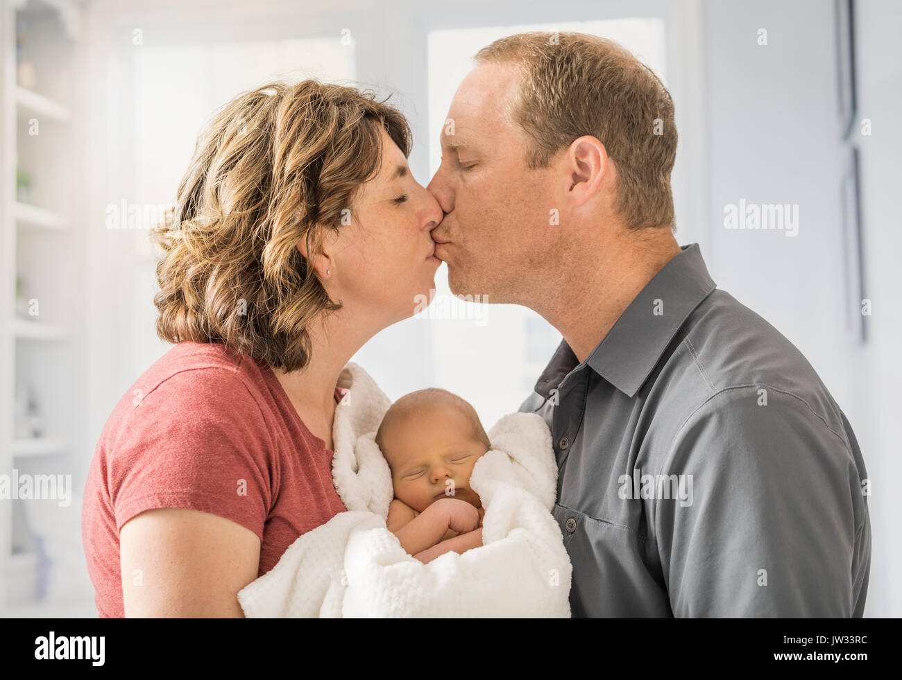 Eltern halten und Sohn (0-1 Monate) und küssen einander Stockfoto