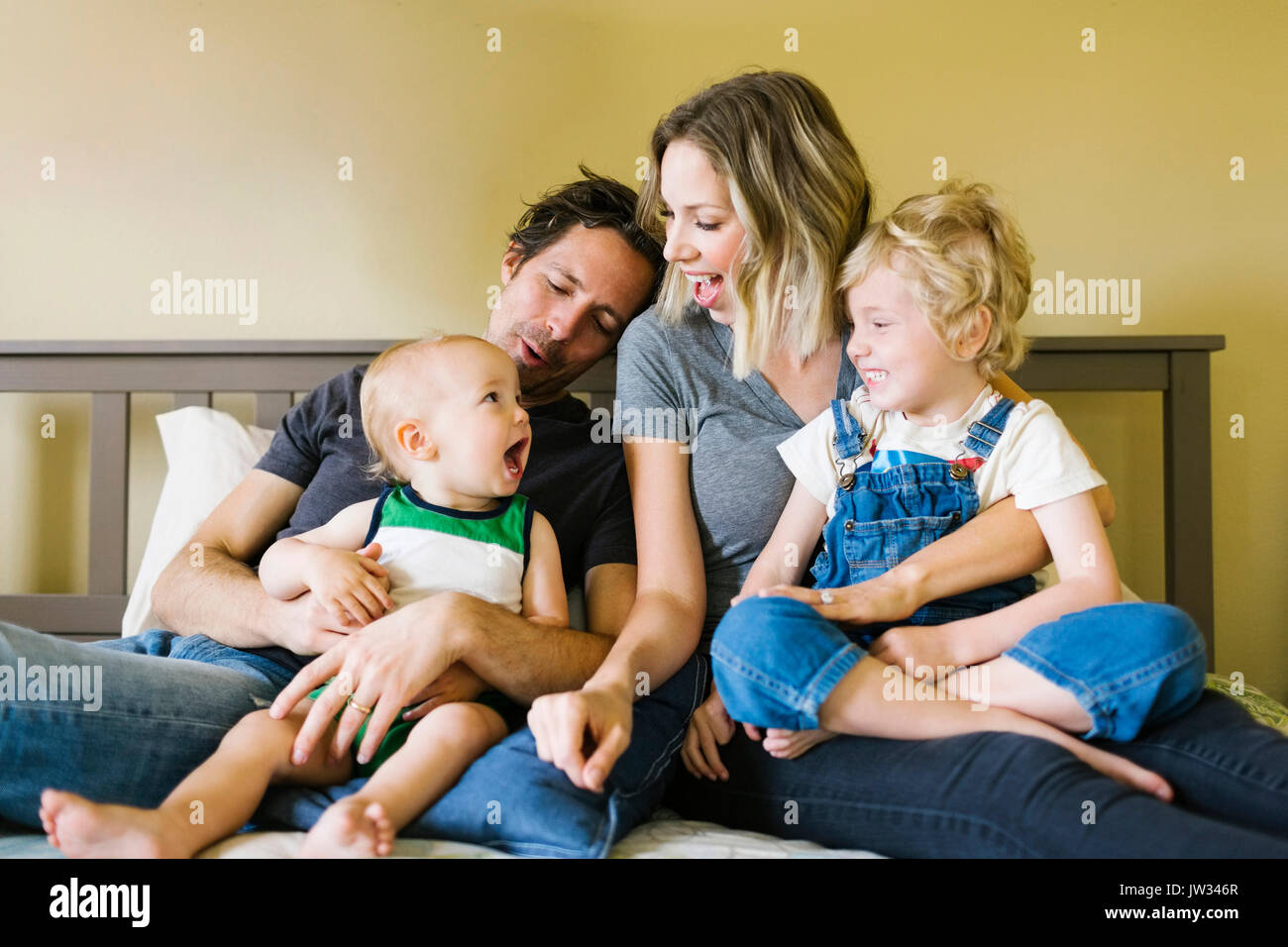 Eltern spielen mit Kinder (12-17 Monate, 4-5) auf Bett Stockfoto