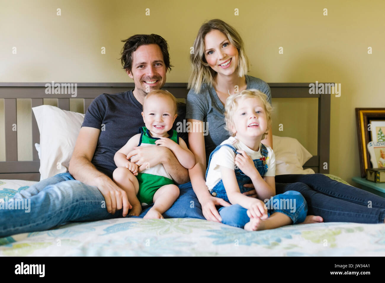 Portrait von Eltern mit Kinder (12-17 Monate, 4-5) auf Bett Stockfoto