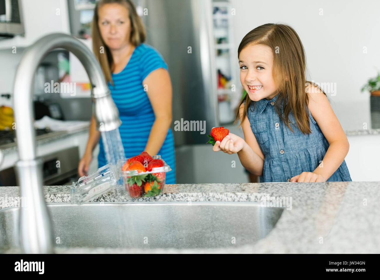 Mutter an Tochter (6-7) Holding Erdbeere in der Küche Stockfoto