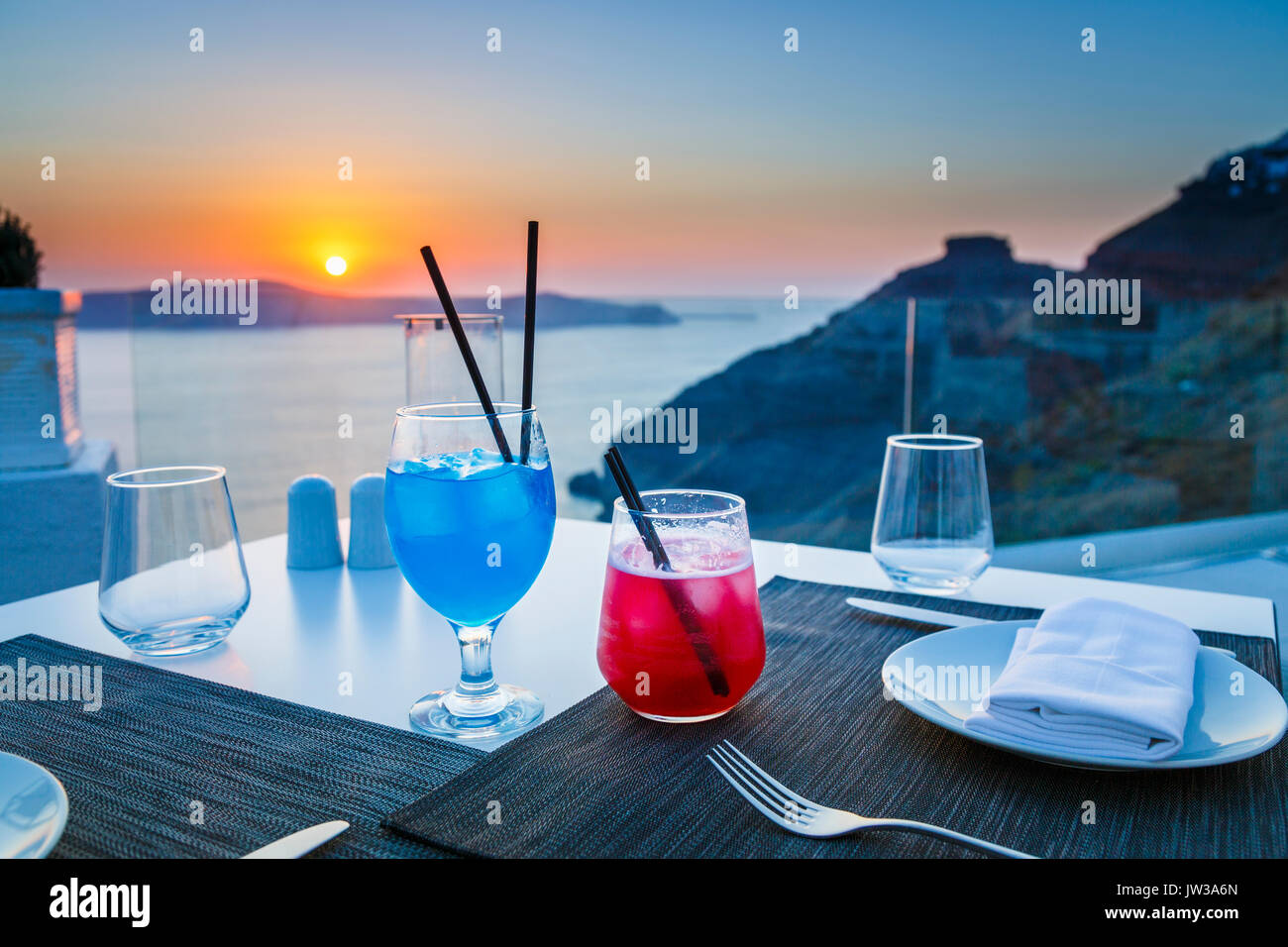 Bunte Cocktails, Imerovigli am Abend, einem Dorf in der Nähe von Fira auf der griechischen Insel Santorini mit der Bezeichnung "Balkon der Ägäis" für seine Sonnenuntergänge Stockfoto