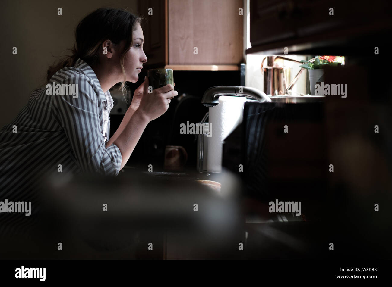 Frau auf der Suche durch Küchenfenster Stockfoto