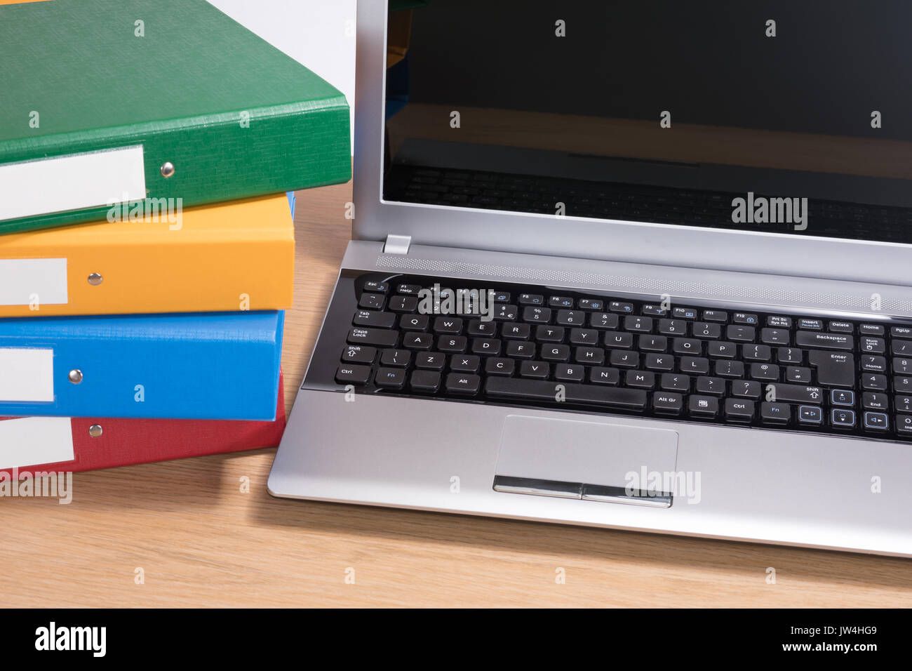 Ein ordentlich Holz Büro Schreibtisch Arbeitsbereich mit offenen Computer Laptop und ordentlich gestapelt Dokumentordnern. Stockfoto