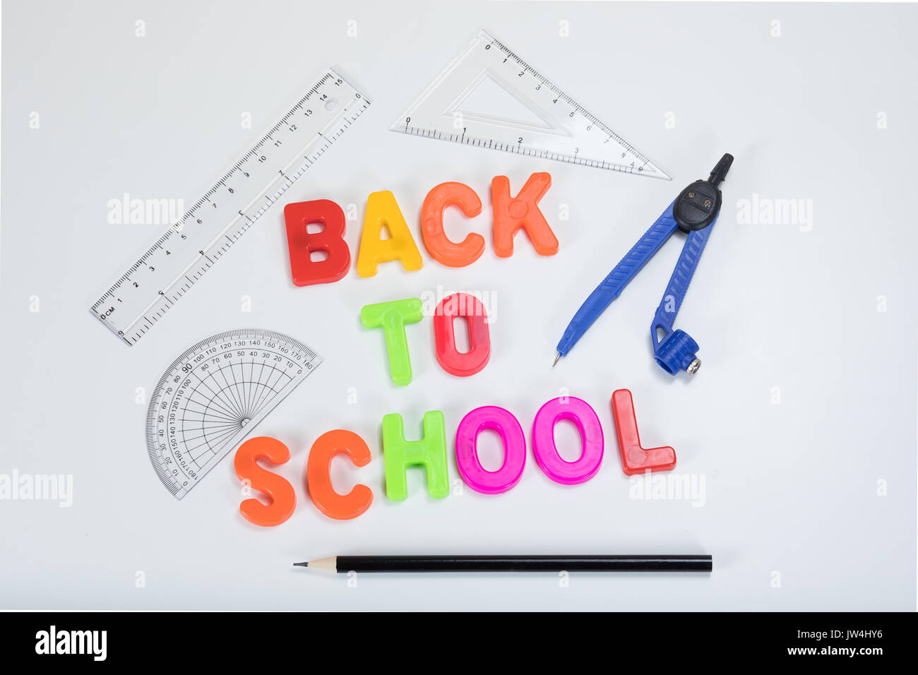 Zurück zu Schule mit bunten Alphabet lernen Buchstaben neben einem Bleistift, Winkelmesser, Lineal und Geometrie liefert auf ein normales weißes backgroun geschrieben Stockfoto