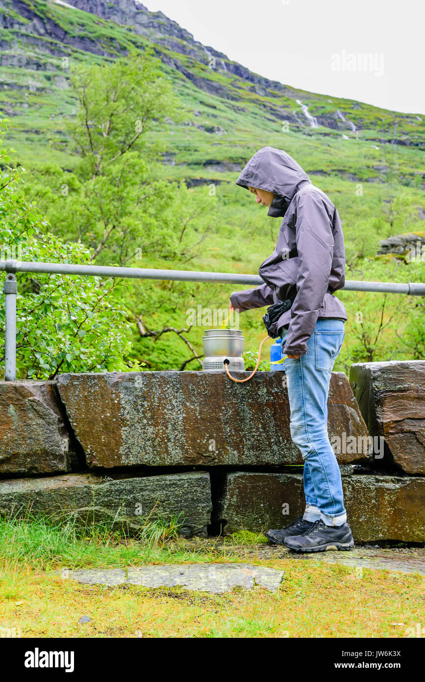 Jungen Erwachsenen männlichen Kochen im Freien auf Campingkocher bei Regenwetter. Stockfoto