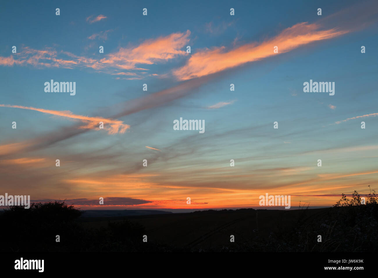 Dunkler Himmel mit rosa und orange Wolken in Sussex. Stockfoto