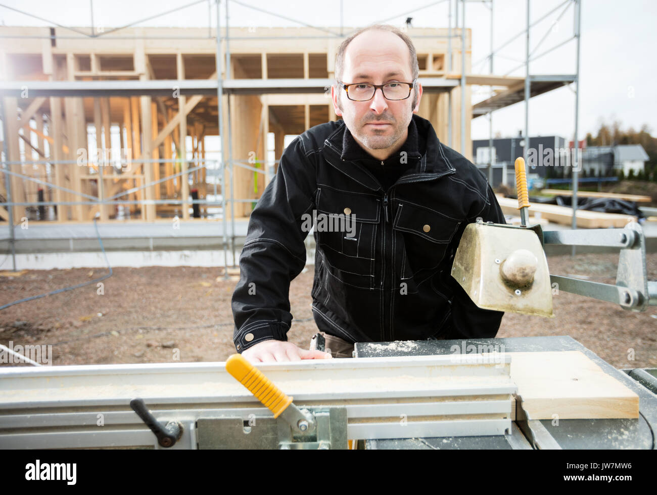 Portrait von zuversichtlich männliche Tischler mit Tisch sah Plank an der Baustelle zu schneiden Stockfoto