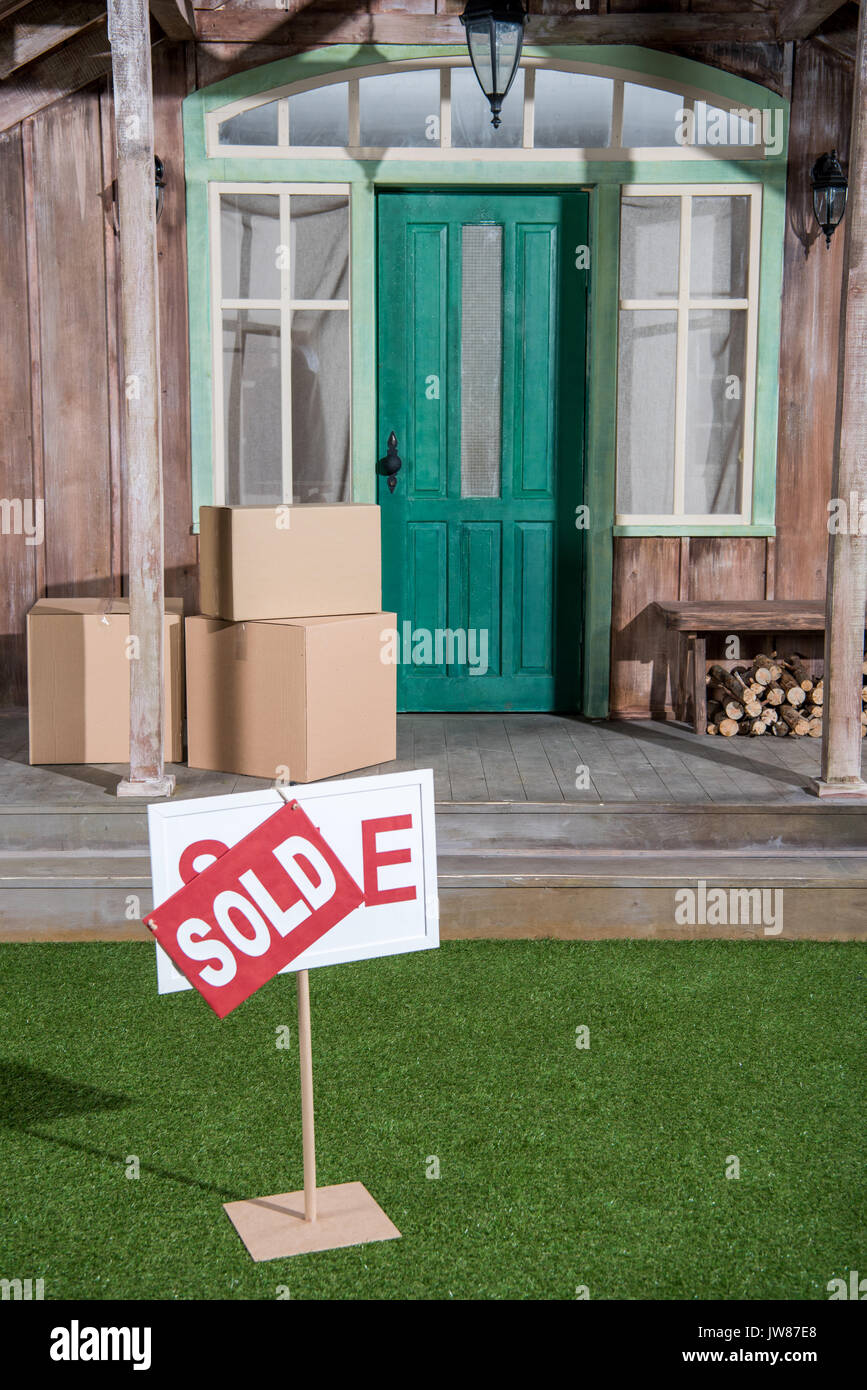 Nahaufnahme der Zeichen auf grünem Gras und Kartons stapeln auf der Veranda verkauft Stockfoto