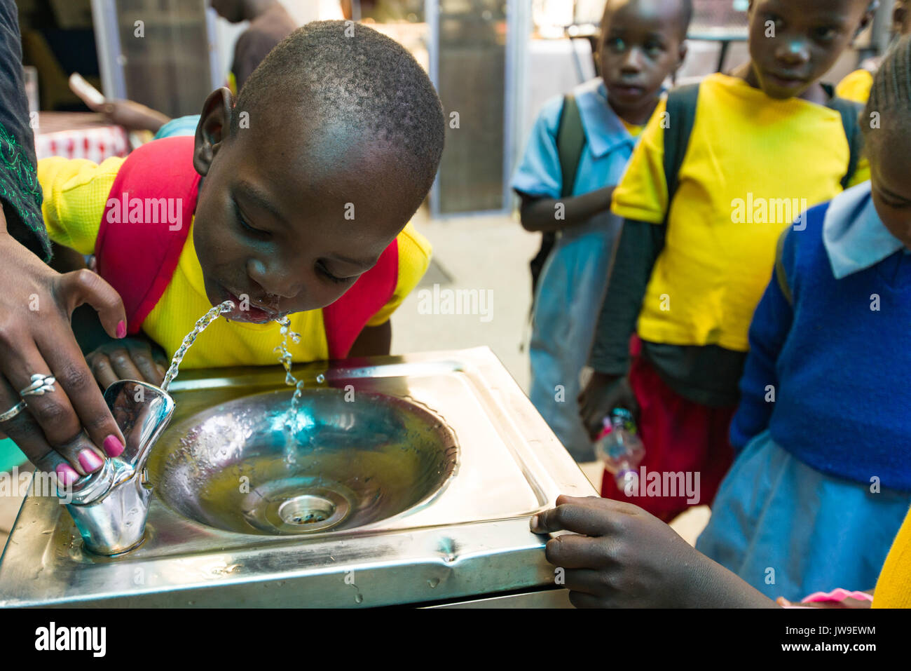 Junge Schüler aus Kibera Trinkwasser aus Brunnen in Kibera, Stadtzentrum, Nairobi, Kenia Stockfoto