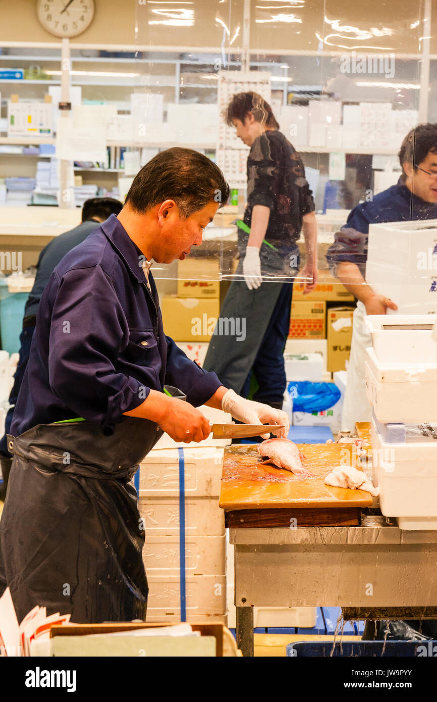 Mann in Fisch Hetzer bei kleinen Tisch ausnehmen Fische mit einem filetiermesser an Omicho, Innen- Markt mit frischen Lebensmitteln, Kanazawa, Japan. Stockfoto