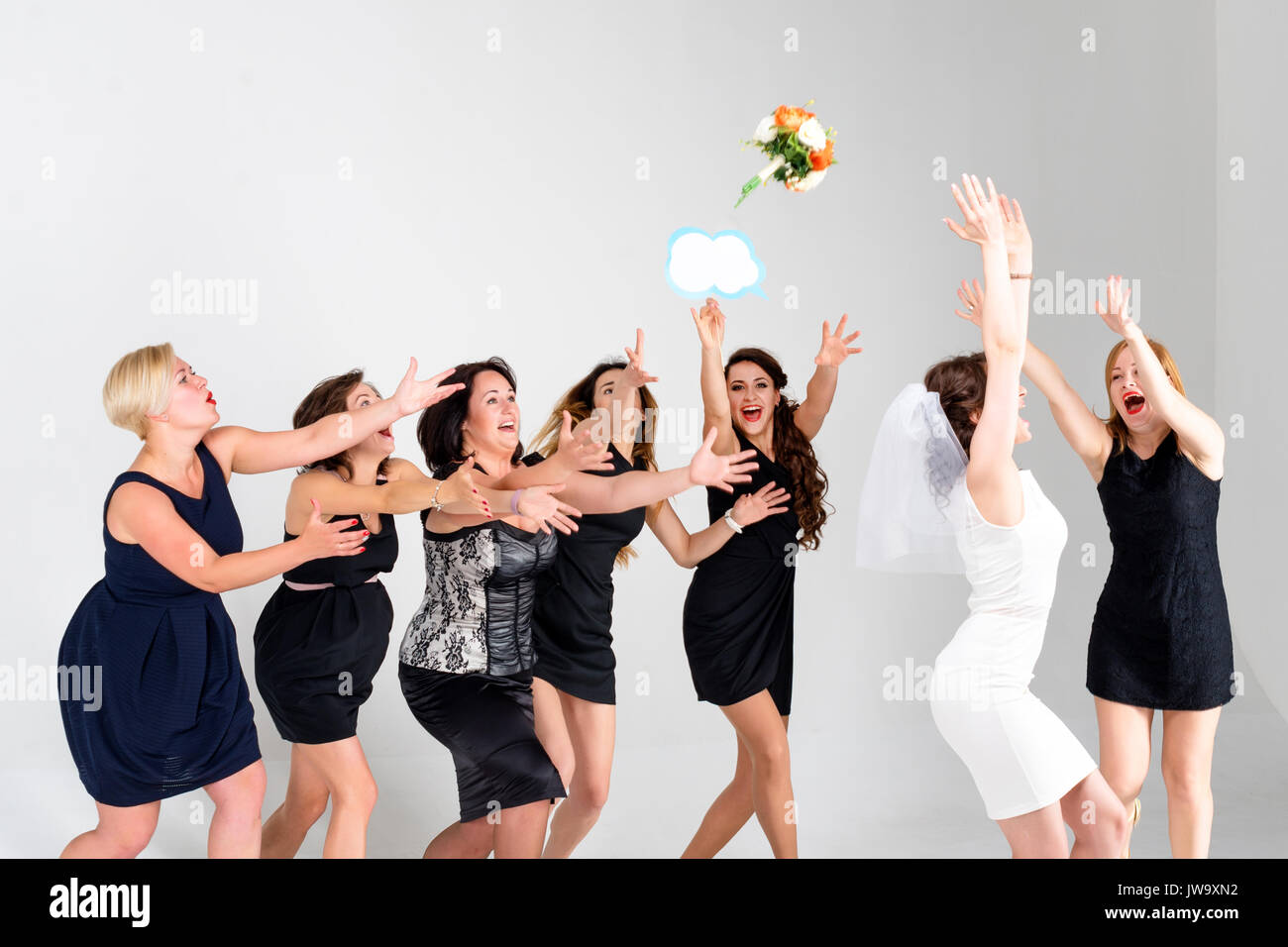 Stilvolle Brautjungfern Spaß mit Braut. Fröhliche glückliche Mädchen feiern eine Bachelorette Party der Braut. Braut werfen Blumenstrauß für Mädchen zu fangen. Studio schießen. Stockfoto