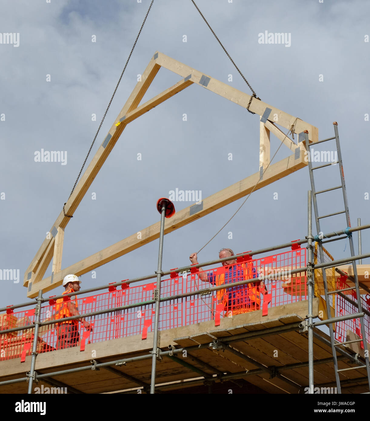 Holz- ein Frame per Kran auf ein neues Haus Dach abgesenkt wird. Stockfoto