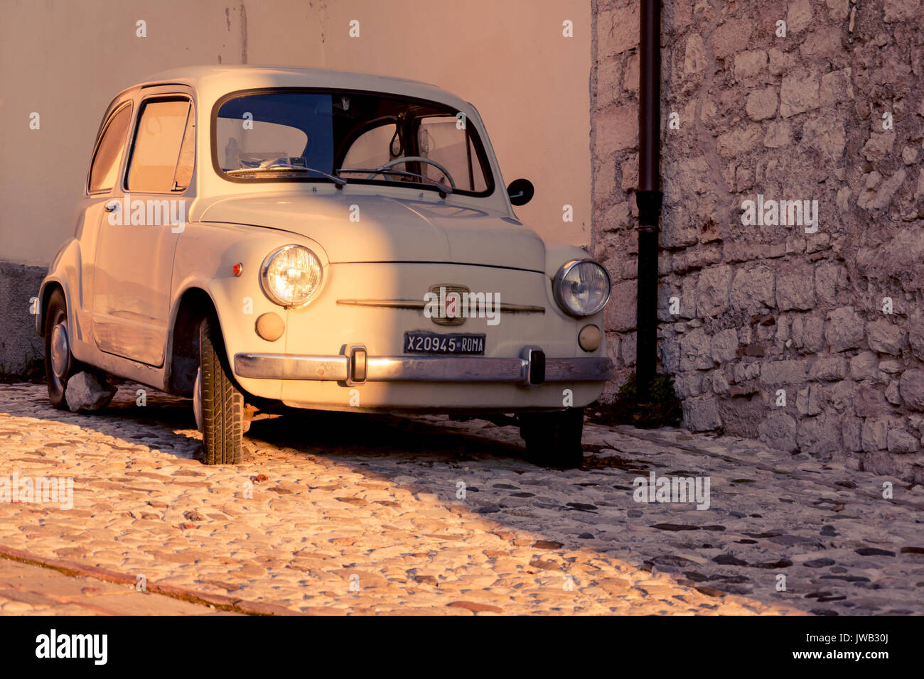 Vintage Fiat 500 auf der Straße einer mittelalterlichen Stadt geparkt. Italien, 2011. Querformat. Stockfoto