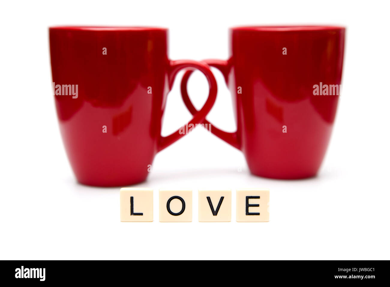 Liebe buchstabiert in Fliesen mit zwei Tassen Kaffee Stockfoto