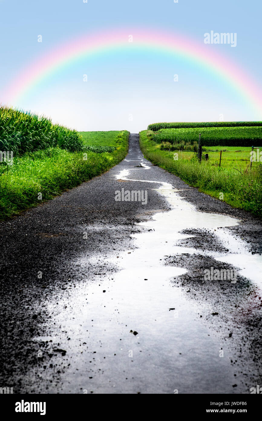 Nasse Straße nach dem Regen in ländlichen Bauernhof mit Rainbow Stockfoto
