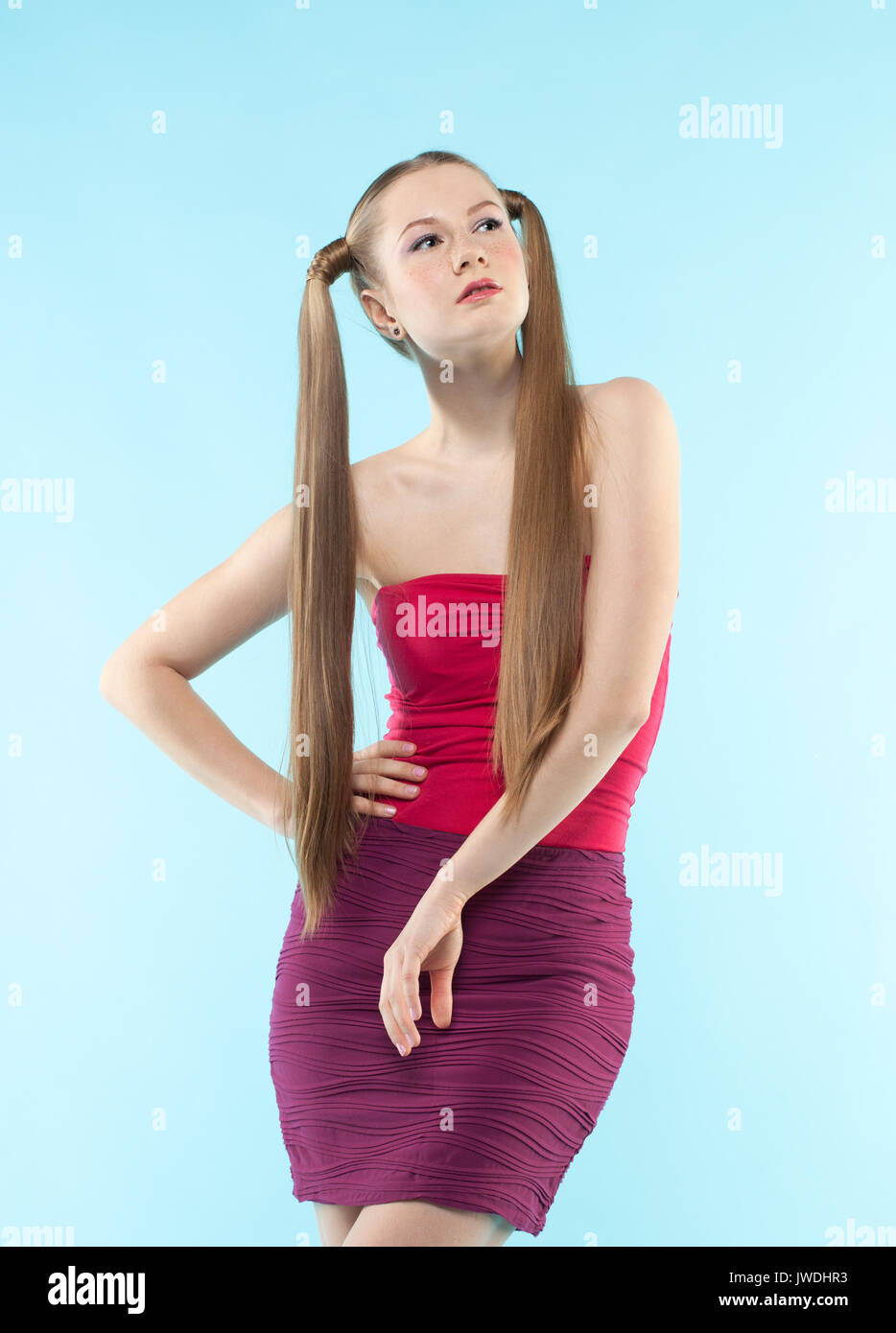 Schönen verspielten sommersprossiges Mädchen im roten Kleid auf blauem Hintergrund Stockfoto